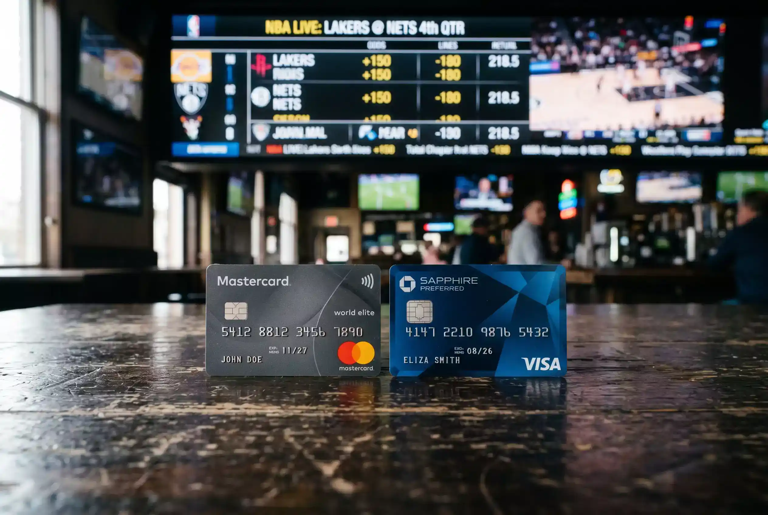 Mastercard und Visa nebeneinander auf einem Tisch mit Sportwetten-Symbolen im Hintergrund